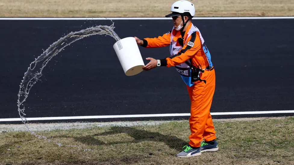 Marshals used a variety of implements, including buckets and upside-down traffic cones, to water the grass around the Suzuka circuit before qualifying