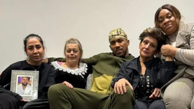 Anthony Joshua sat pictured with his mum (right) and family members of the victims including the mothers of Ghami and Ayodele